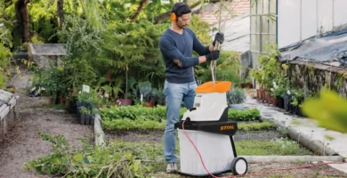 Jardinero usando una biotrituradora eléctrica silenciosa para triturar ramas.